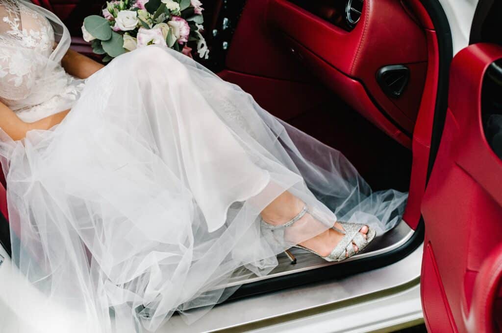 Mariée entrant dans voiture rouge en robe blanche